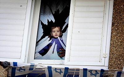 A father and his baby look out the shattered window of their house that was hit by shrapnel from a Grad rocket that landed in Netivot on Monday,  November 12 (photo credit: Edi Israel/Flash90)