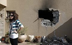 An Israeli woman stands outside a house damaged by a rocket fired from the Gaza Strip on Friday, Nov. 16 (photo credit: Tsafrir Abayov/Flash90)