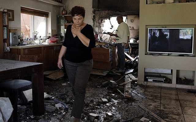 An Israeli woman walks through a house in southern Israel that was hit by a rocket fired from the Gaza Strip during Operation Pillar of Defense (photo credit: Tsafrir Abayov/Flash90)