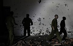 Soldiers examine a damaged wall of a house in the Be'er Tuvia region that was hit by a rocket fired from the Gaza Strip on Friday, Nov. 16 (photo credit: Tsafrir Abayov/Flash90)
