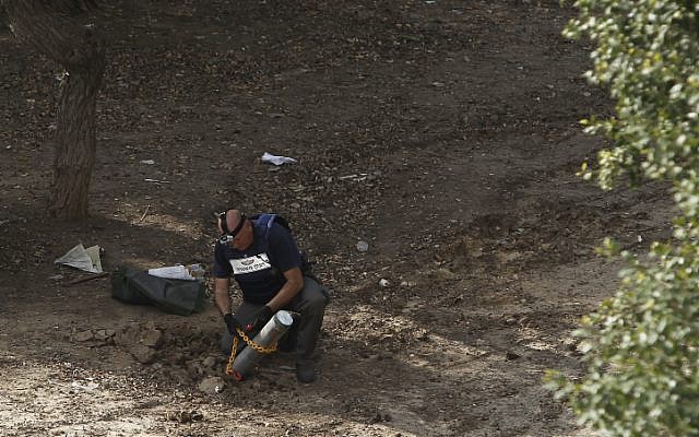 Israeli police remove the remains of a rocket, fired by Palestinian terrorists from the Gaza Strip, that landed near buildings in the coastal city of Ashkelon, Nov, 2012. (photo credit: Tsafrir Abayov/Flash90)