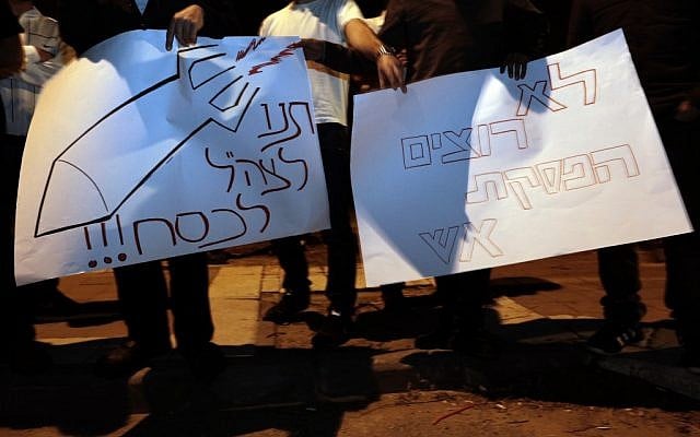 Israelis hold signs protesting the ceasefire in Kiryat Malachi on Wednesday night. (photo credit: Tsafrir Abayov/Flash90)