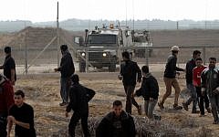Palestinians retreat from the border fence between Israel and the southern Gaza Strip as an IDF patrol approaches in 2012. (photo credit: Abed Rahim Khatib/Flash90/File)