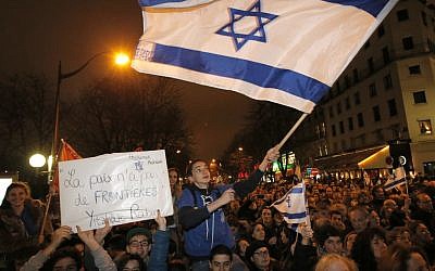 Supporters wave Israeli flags during a Tuesday gathering near the Israeli embassy in Paris. (Francois Mori/AP)
