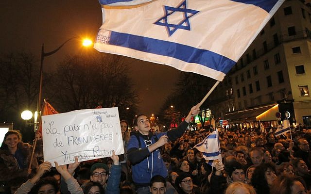 Supporters wave Israeli flags during a Tuesday gathering near the Israeli embassy in Paris. (Francois Mori/AP)