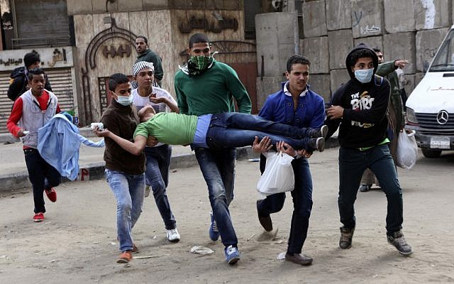 Egyptians carry a protester wounded in clashes with security forces near Tahrir square, where an opposition rally has been called for to voice rejection of President Morsi's seizure of near absolute powers, in Cairo on Tuesday, Nov. 27, 2012 (photo credit: AP/Peter Hartwell)
