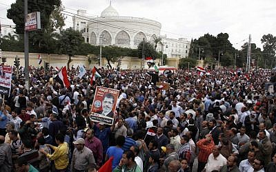 Supporters of Egyptian President Mohammed Morsi chant slogans and wave his campaign posters outside the Presidential palace, background, in Cairo, Egypt, Friday, Nov. 23 (photo credit: AP/Ahmed Abd el Fatah)