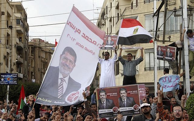 Supporters of Egyptian President Mohammed Morsi chant slogans and wave his campaign posters and a national flag outside the Presidential Palace in Cairo, Egypt, Friday, Nov. 23 (photo credit: AP/Ahmed Gomaa)