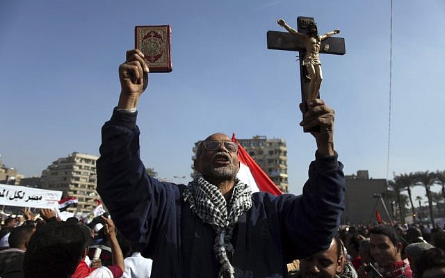 An Egyptian protesters holds a cross and a Quran as he chants anti-Muslim Brotherhood slogans at an opposition rally in Tahrir Square, in Cairo, Egypt, Friday, Nov. 30 (photo credit: AP/Khalil Hamra)