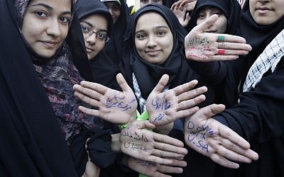 Iranians show their hands, with writing in Persian in support Supreme Leader Ayatollah Ali Khamenei, denouncing the U.S. and one of them with the word "Nuclear Scientist," during an annual state-backed rally in front of the former US Embassy in Tehran, Iran, Friday, Nov. 2, 2012. (photo credit: AP)