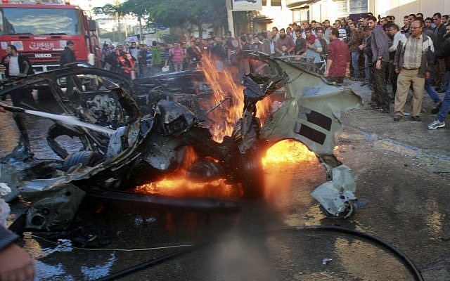 People look at the wreckage of the car in which Ahmed Jabari, head of the Hamas military wing, was killed in an Israeli airstrike, Gaza City, Wednesday, November 14, 2012 (photo credit: AP/Adel Hana)