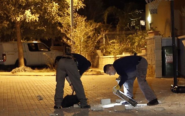 Police explosives experts collect a Kassam rocket at a residential area near the Israel-Gaza border in southern Israel, Saturday, November 10 (photo credit: AP/Tsafrir Abayov) Police explosives experts collect a Kassam rocket at a residential area near the Israel-Gaza border in southern Israel, Saturday, November 10 (photo credit: AP/Tsafrir Abayov)