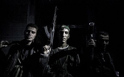 In this file photo from October 2012, Syrian rebel fighters belonging to the Liwa al-Tawhid unit pose after several days of intense clashes in Aleppo (photo credit: AP Photo/Narciso Contreras, File)
