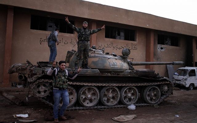 Syrian fighters celebrate their victory on top of a tank they took after storming a military base in Aleppo, Monday, Nov. 19, 2012. (photo credit: Khalil Hamra/AP)