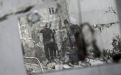 In this illustrative photo, rebel fighters watch over their enemy's position as they prepare themselves to shoot a shoulder-fired rocket towards a Syrian army tank in the Karm al-Jebel neighborhood of Aleppo, Syria. (AP Photo/Narciso Contreras)