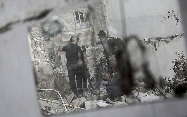 In this illustrative photo, rebel fighters watch over their enemy's position as they prepare themselves to shoot a shoulder-fired rocket towards a Syrian army tank in the Karm al-Jebel neighborhood of Aleppo, Syria. (AP Photo/Narciso Contreras)