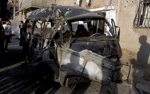 Syrians standing near a damaged vehicle after an attack in Damascus, Syria, Wednesday, Nov. 7 (photo credit: AP/SANA)