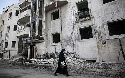 A Syrian woman walks in front of a destroyed hospital on the outskirts of Aleppo, Syria earlier this month (photo credit: AP/Narciso Contreras)