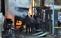 Syrian citizens stand near a burning truck that was destroyed by two car bombs, at Jaramana neighborhood, in the suburb of Damascus, Syria, Wednesday, Nov. 28 (photo credit: AP/SANA)