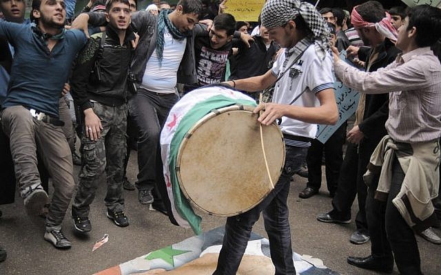 Young Syrians demonstrate against Syrian President Bashar Assad, depicted on the poster beneath the feet of a drummer, in the Bustan al-Qasr neighborhood of Aleppo, Syria, Friday, Nov. 9 (photo credit: AP/Monica G. Prieto)