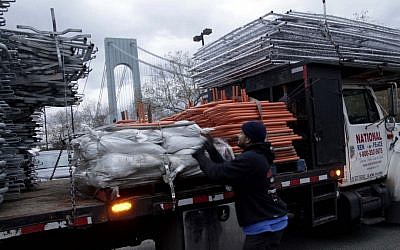Pedro Cabrera stops setting up a barrier near the starting line of the NYC Marathon in Staten Island and secures his company's gear after the cancellation of the race on Friday (photo credit: AP/Seth Wenig)