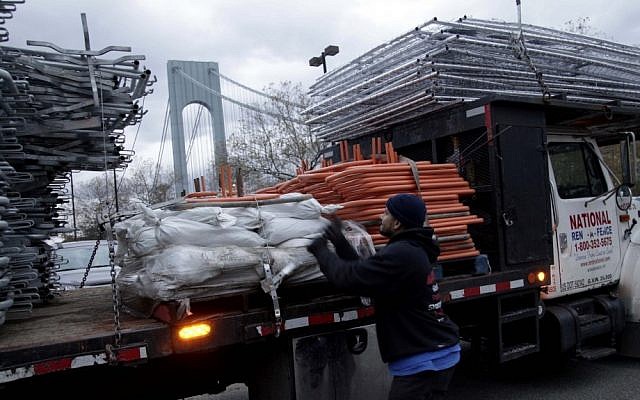 Pedro Cabrera stops setting up a barrier near the starting line of the NYC Marathon in Staten Island and secures his company's gear after the cancellation of the race on Friday (photo credit: AP/Seth Wenig)