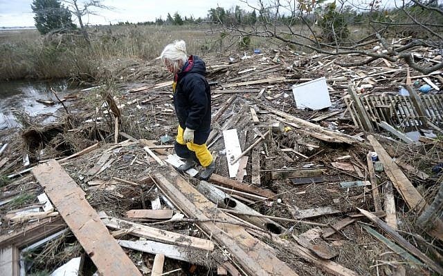 Tricia Burke walks over debris which washed up onto her property in the wake of superstorm Sandy, Thursday, Nov. 1, 2012, in Brick, N.J. (photo credit: Julio Cortez/AP)