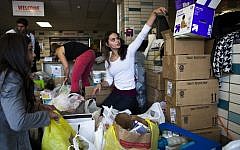 A volunteer helps sort through donations at Hoboken High School in Hoboken, New Jersey, on Sunday as surrounding neighborhoods remain without power due to damage caused by superstorm Sandy (photo credit: AP/John Minchillo)