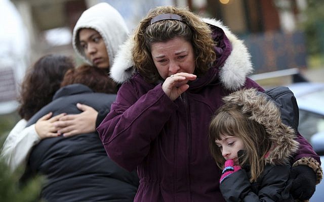 Mourners grieve at one of the makeshift memorials for victims of the Sandy Hook Elementary School shooting on Sunday. (photo credit: AP/Mary Altaffer) Mourners grieve at one of the makeshift memorials for victims of the Sandy Hook Elementary School shooting on Sunday. (photo credit: AP/Mary Altaffer)
