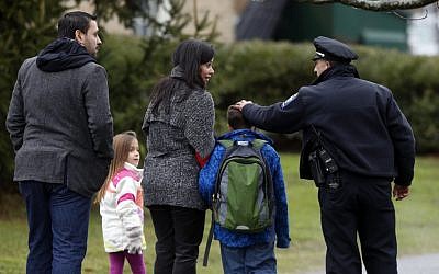 A police officer greets a returning student as he is walked into Hawley School in Newtown, Conn., Tuesday, Dec. 18, 2012. (photo credit: Jason DeCrow/AP)