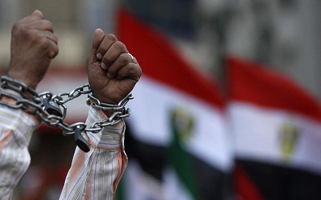 A protester shows his chained hands during a demonstration in Tahrir Square in Cairo, Egypt, on Friday against a constitution drafted by Islamist supporters of President Mohammed Morsi (photo credit: AP/Petr David Josek)