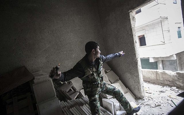 A rebel fighter throws a grenade toward Syrian troops loyal to President Bashar Assad during clashes in Aleppo, Syria, on Friday, Dec. 7 (photo credit: AP/Narciso Contreras) A rebel fighter throws a grenade toward Syrian troops loyal to President Bashar Assad during clashes in Aleppo, Syria, on Friday, Dec. 7 (photo credit: AP/Narciso Contreras)