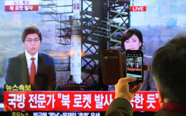 A South Korean man uses his smartphone to take a picture of a television screen reporting news of North Korea's rocket launch, at Seoul Railway Station in Seoul, South Korea, Wednesday, December 12, 2012. The letters on the screen read 'North Korea's rocket launch seems to be successful.' (photo credit: AP/Ahn Young-joon)