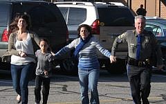 A police officer leads two women and a child from Sandy Hook Elementary School in Newtown, Connecticut, where a gunman opened fire, killing 26 people, including 20 children, December 14, 2012. (AP/Newtown Bee/Shannon Hicks)