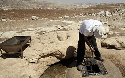 A man draws water from a well in the West Bank (photo credit: Abir Sultan/Flash90)