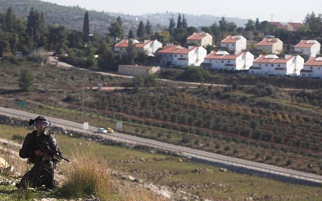 An Israeli soldier between the Palestinian village of Nabi Saleh (not pictured) and the Jewish settlement of Halamish during a demonstration against settlement activity in December 2012 (photo credit: Issam Rimawi/Flash90)