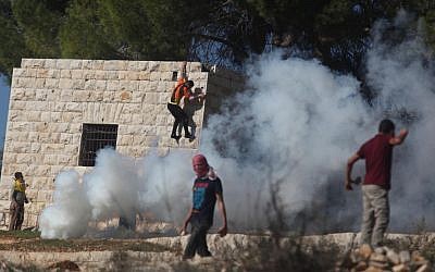 A Palestinian protester hurls stones at Israeli soldiers during a protest against settlement activity in the West Bank village of Nabi Saleh near Ramallah, Friday, November 30, 2012 (photo credit: Issam Rimawi/Flash90)
