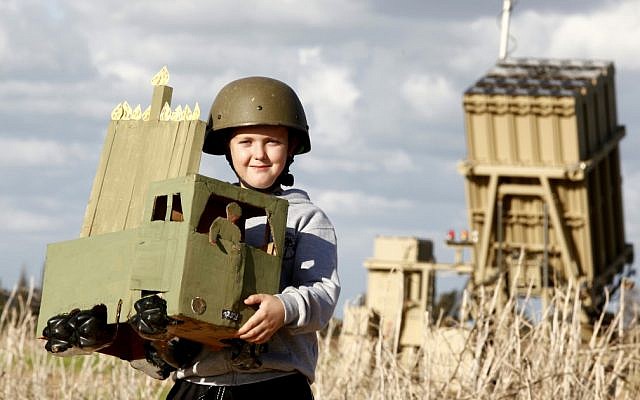 A child in Ashkelon holds a homemade Menorah in front of the Iron Dome unit stationed in the city.  The holiday of Hanukkah begins Saturday night (photo credit: Edi Israel/FLASH90)