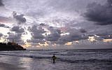 A lone surfer walks along the stormy shoreline of Tel-Aviv (photo credit: Tomer Neuberg/Flash90)