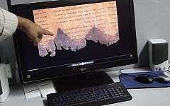An Israel Antiquities Authority worker points to a spectral image photograph of fragments of the Dead Sea scrolls, at the Israel Museum in Jerusalem on Wednesday, December 18 (photo credit: Miriam Alster/Flash90)