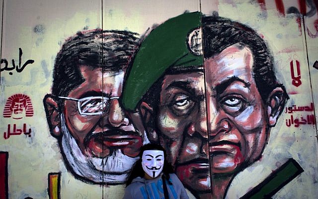 A mural on the exterior wall of the presidential palace depicting President Mohammed Morsi, left, former military council ruler Hussein Tantawi, center, and ousted president Hosni Mubarak with Arabic that reads "no, the brotherhood's constitution is not valid," in Cairo, Egypt, Dec. 8, 2012. (photo credit: Nasser Nasser/AP)