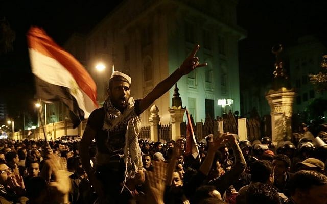 Egyptian protesters chant anti Muslim Brotherhood and Egyptian President Mohammed Mosri slogans outside the presidential palace after they broke a barbed wire barricade keeping them from getting closer to the presidential palace, in Cairo, Egypt, on Friday, December 7. (photo credit: AP/Hassan Ammar) Egyptian protesters chant anti Muslim Brotherhood and Egyptian President Mohammed Mosri slogans outside the presidential palace after they broke a barbed wire barricade keeping them from getting closer to the presidential palace, in Cairo, Egypt, on Friday, December 7. (photo credit: AP/Hassan Ammar)