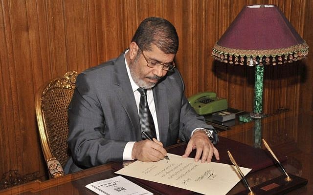 Then-Egyptian President Mohammed Morsi signs into law the country's Islamist-backed constitution in December 2012. (photo credit: AP/Egyptian Presidency)