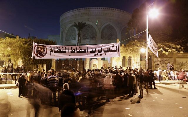 Egyptian protesters chant anti-Muslim Brotherhood and anti-Morsi slogans outside the presidential palace, under a banner with a  that reads 'the people want to bring down the regime,' in Cairo, Egypt on Saturday, December 8, 2012. (photo credit: AP Photo/Hassan Ammar)