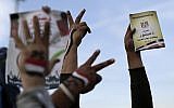Supporters of President Mohammed Morsi with the Egyptian national flag painted on their hands, flash victory signs as one holds a copy of Egypt's draft constitution, right, during a demonstration, in Cairo, Egypt, Tuesday, Dec. 11, 2012. (photo credit: AP/Hassan Ammar)