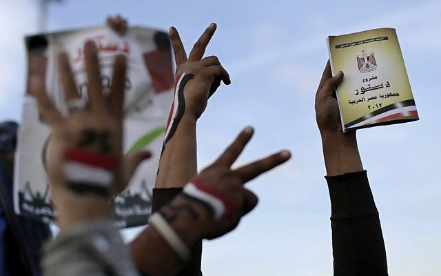 Supporters of President Mohammed Morsi with the Egyptian national flag painted on their hands, flash victory signs as one holds a copy of Egypt's draft constitution, right, during a demonstration, in Cairo, Egypt, Tuesday, Dec. 11, 2012. (photo credit: AP/Hassan Ammar) Supporters of President Mohammed Morsi with the Egyptian national flag painted on their hands, flash victory signs as one holds a copy of Egypt's draft constitution, right, during a demonstration, in Cairo, Egypt, Tuesday, Dec. 11, 2012. (photo credit: AP/Hassan Ammar)
