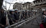 Egyptian riot police stand guard behind barbed wire, while protesters chant anti-Muslim Brotherhood slogans during a demonstration in front of the Presidential Palace, in Cairo, Egypt, Tuesday, December 4, 2012. (photo credit: AP/Nasser Nasser)