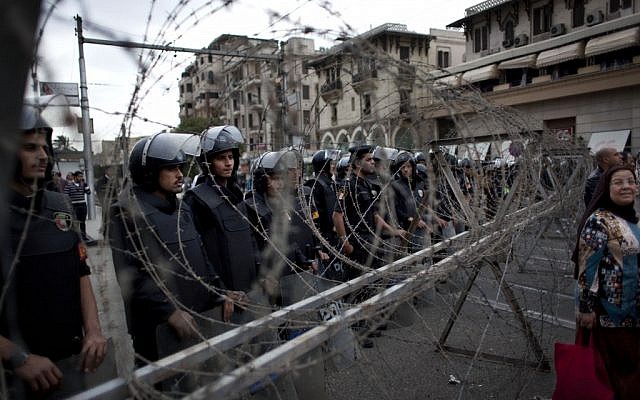 Egyptian riot police stand guard behind barbed wire, while protesters chant anti-Muslim Brotherhood slogans during a demonstration in front of the Presidential Palace, in Cairo, Egypt, Tuesday, December 4, 2012. (photo credit: AP/Nasser Nasser) Egyptian riot police stand guard behind barbed wire, while protesters chant anti-Muslim Brotherhood slogans during a demonstration in front of the Presidential Palace, in Cairo, Egypt, Tuesday, December 4, 2012. (photo credit: AP/Nasser Nasser)