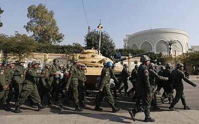 Egyptian soldiers walking past a military tank that secures the presidential palace in Cairo on December 13, 2012. (photo credit: Petr David Josek/AP)
