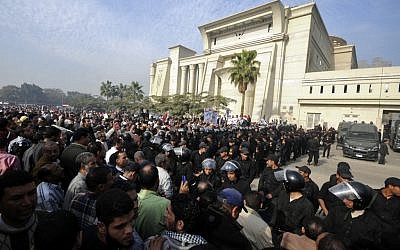 Riot police form a cordon as several thousand supporters of Islamist President Mohammed Morsi surround the Supreme Constitutional Court on Sunday (photo credit: Ahmad Hammad/AP).